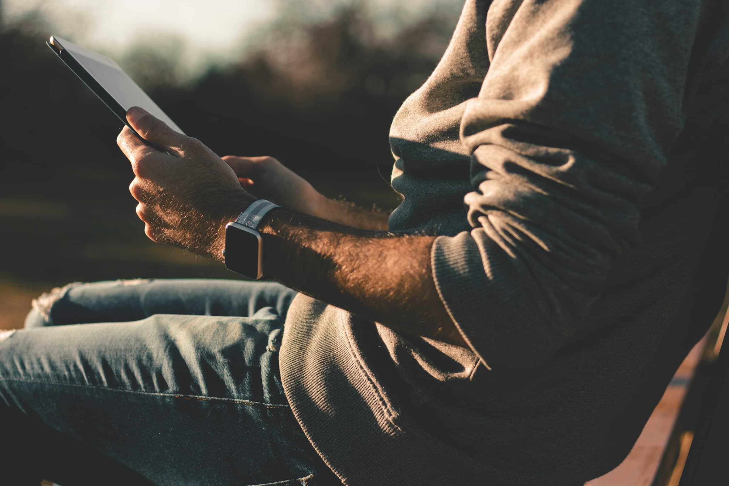 A person outdoors reading a tablet in the evening sun